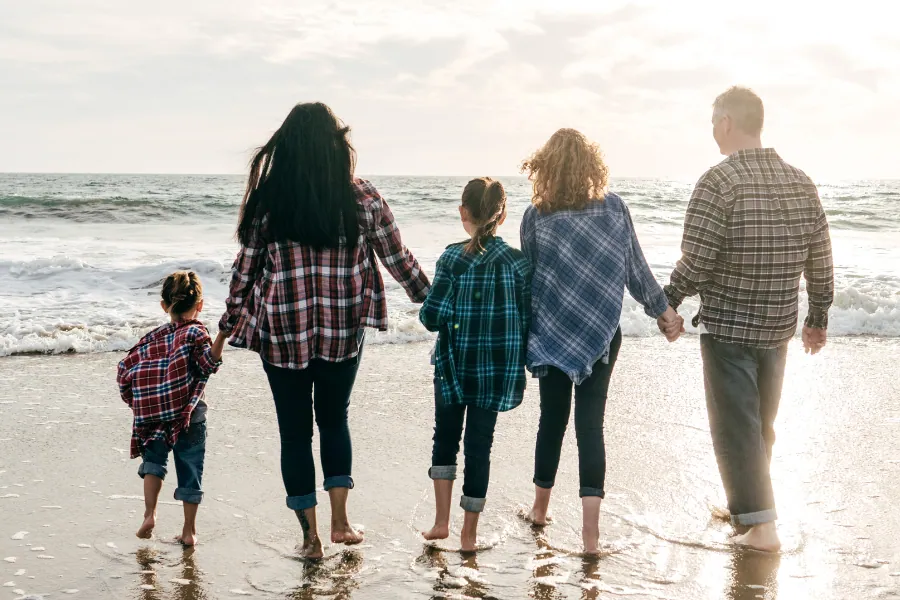 Family holding hands as they walk along the beach towards the sea